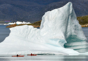 Zwei Kajakfahrer passieren am 03.09.2010 einen Eisberg im Fjord von Narsaq (Grönland). Eisberge entstehen, wenn Gletscher schmelzen. Forschungen zeigen, dass auch die als stabil geltenden Gletscher in Grönland Eis verlieren. (Foto: Wolfgang Heumer/dpa)